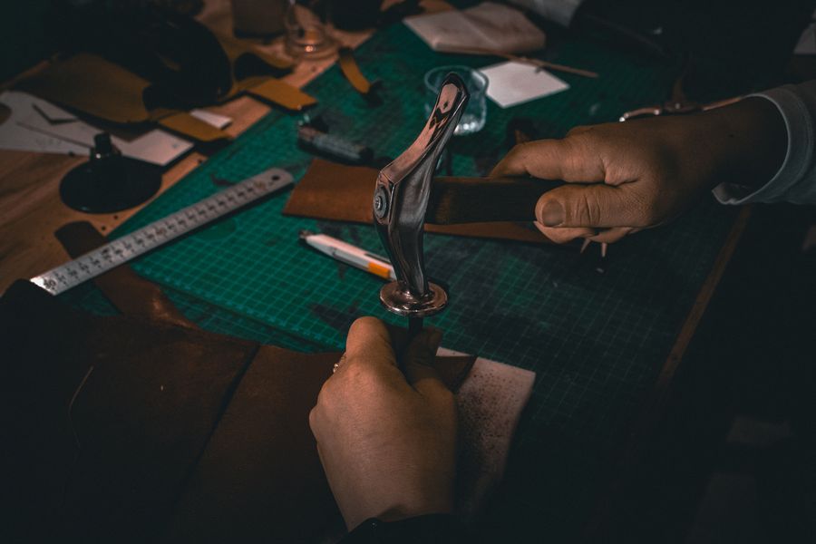Mãos trabalhando couro sob luz quente, ofício artesanal