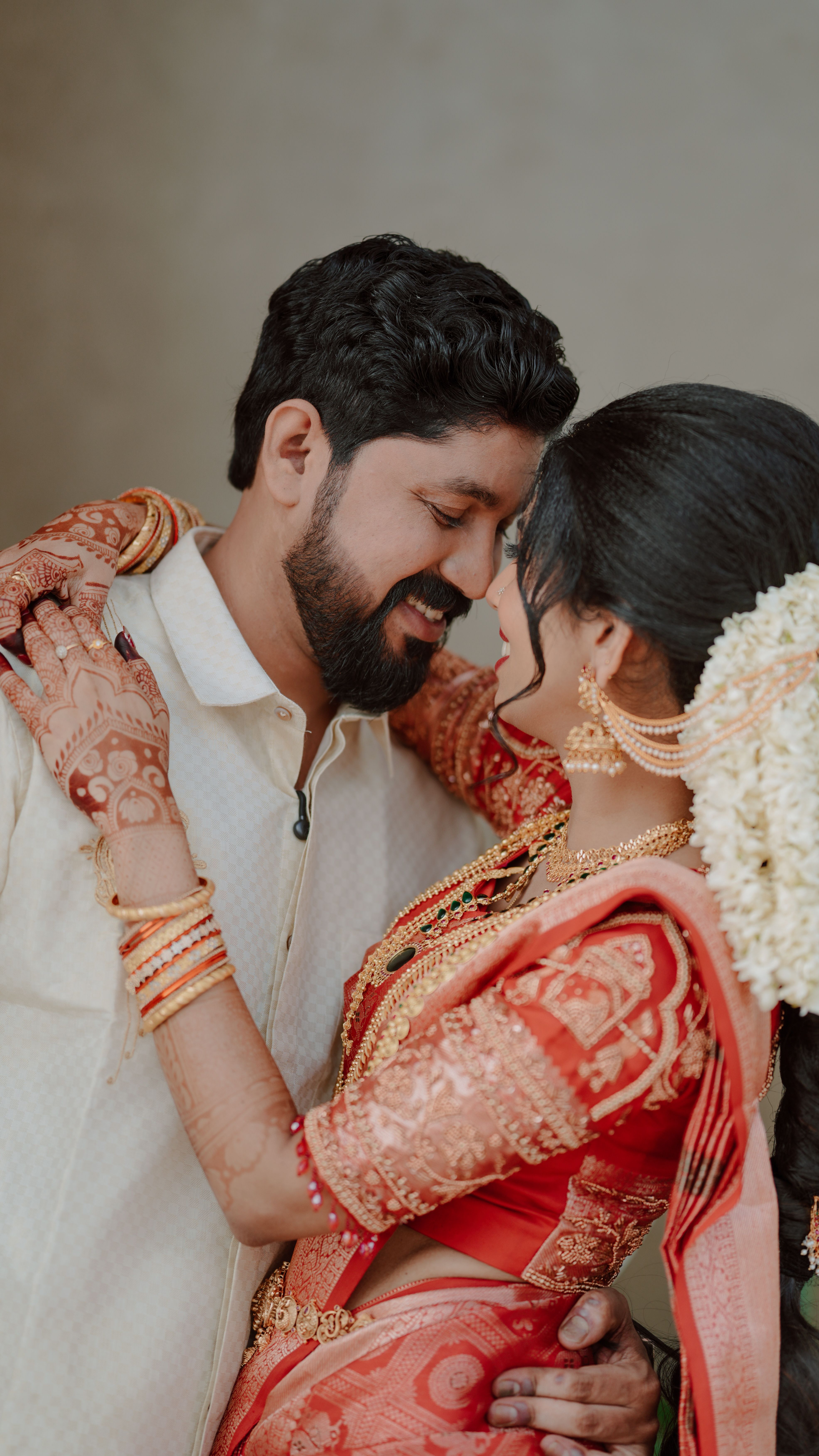 A joyful Indian couple embraces during their traditional wedding ceremony, highlighting love and henna art.