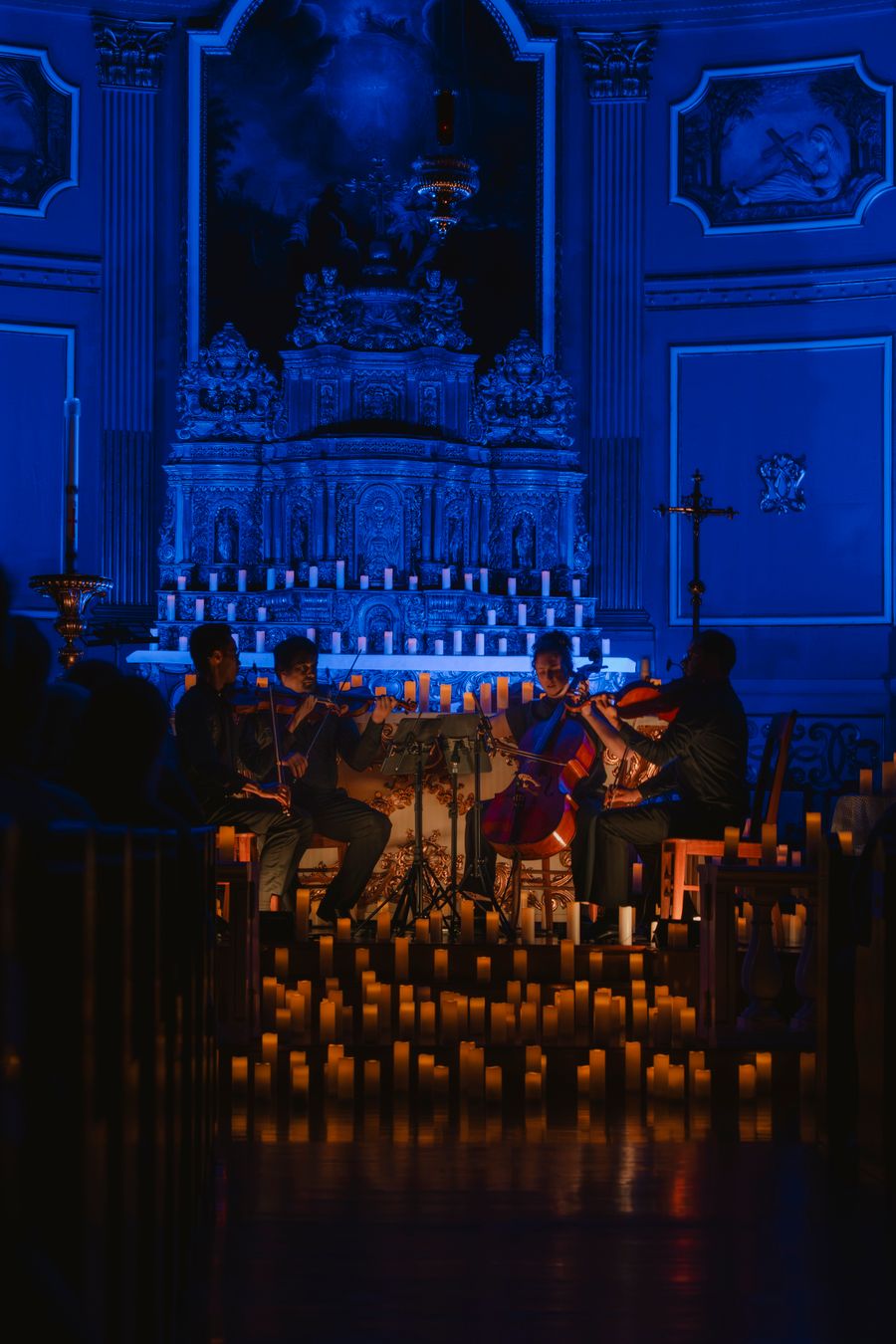 Musicians performing by candlelight inside a historic stone church, the audience seated close around them.