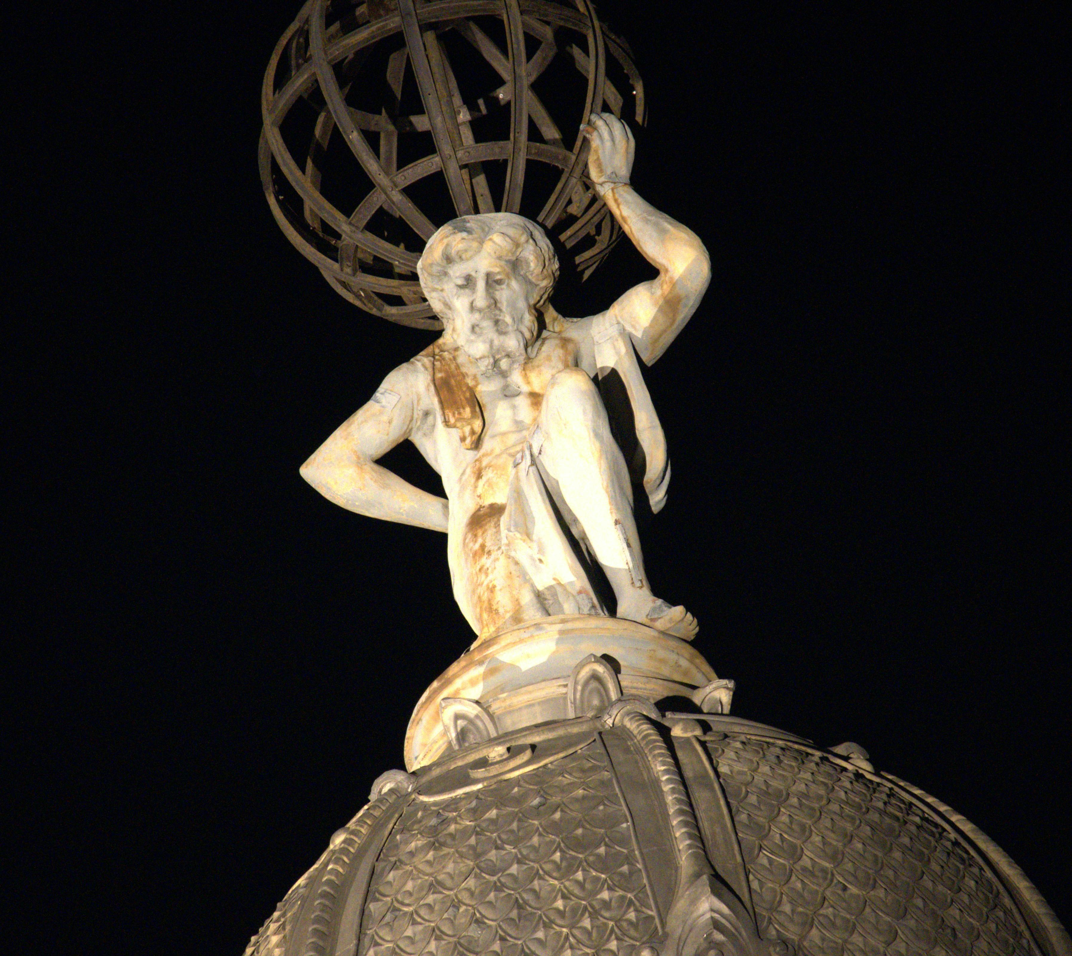 Night view of the Atlas statue atop a building in Montevideo, Uruguay, holding the celestial sphere.