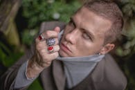 从上方看去，一位穿着高领毛衣、戴着巨大戒指的英俊男子，面无表情却性感地凝视着镜头