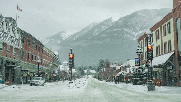 Snow-covered street in Banff, Alberta with mountain backdrop and stoplights