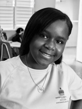 Black and white portrait of a smiling student in a classroom setting.