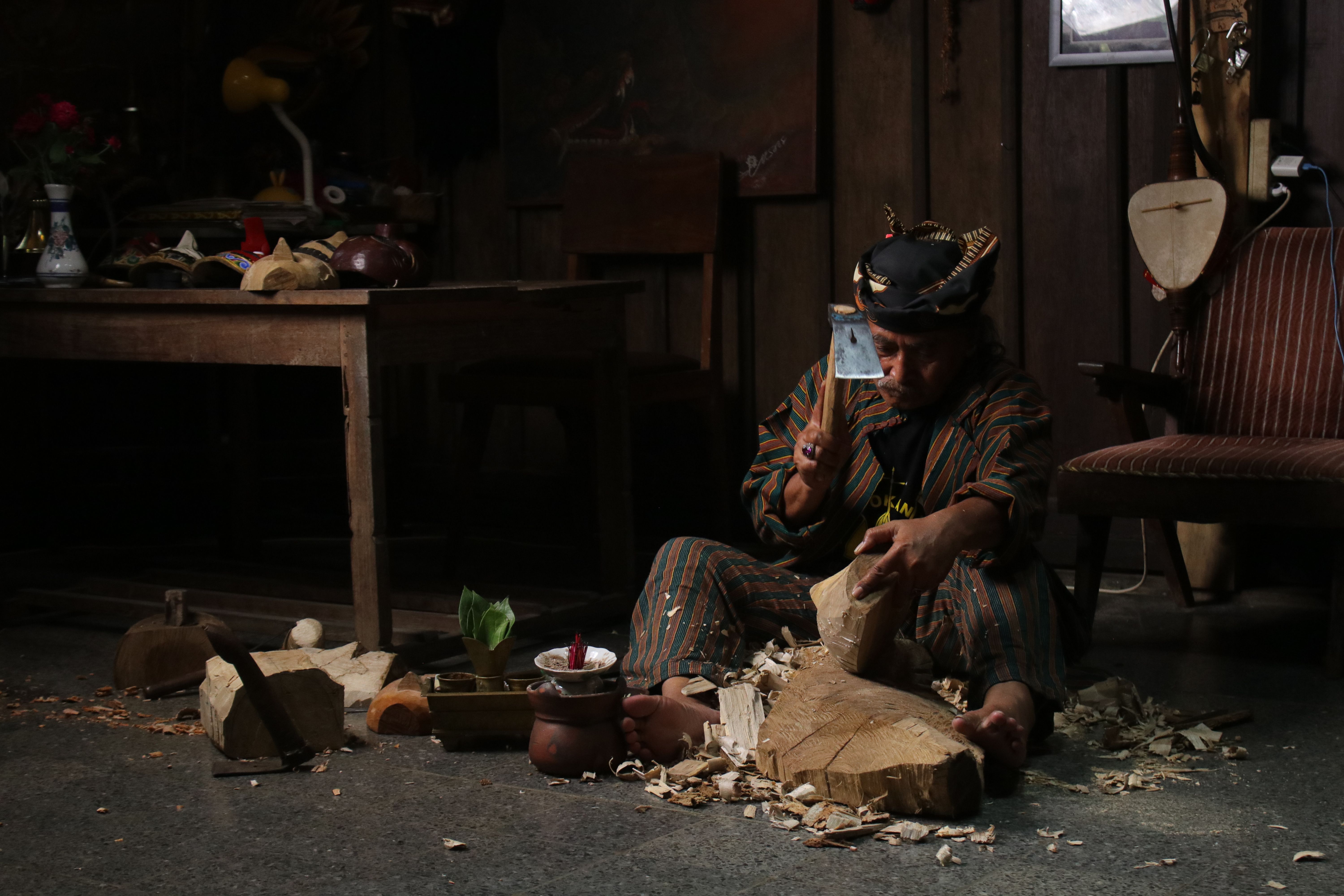A craftsman skillfully carves wood in a traditional workshop. Rustic surroundings emphasize a cultural atmosphere.