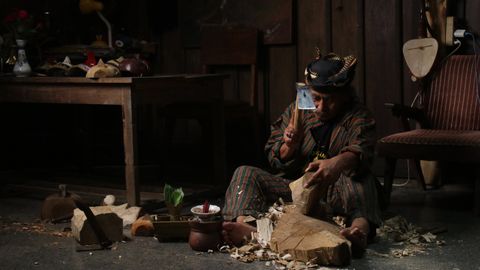 A craftsman skillfully carves wood in a traditional workshop. Rustic surroundings emphasize a cultural atmosphere.