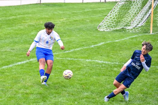 Intense soccer match with two teenagers battling for the ball on a green field.