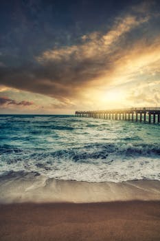 Captivating sunset over Miami beach with crashing waves and a wooden pier.