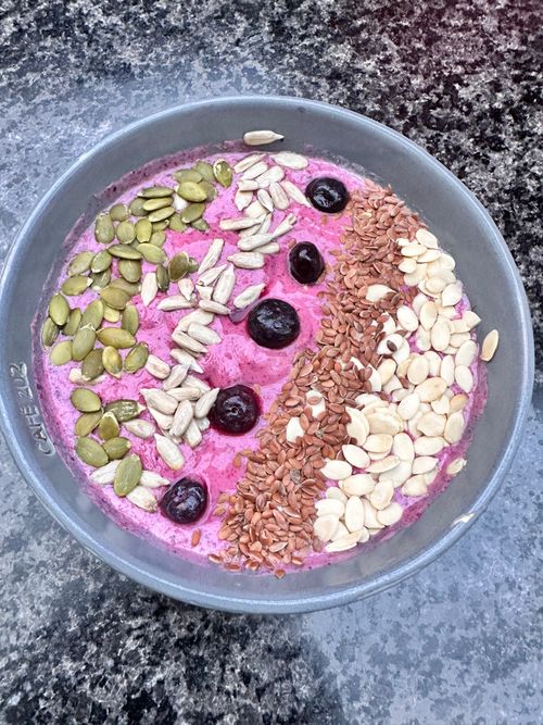 Free Colorful smoothie bowl topped with mixed seeds and cherries on a textured surface. Stock Photo