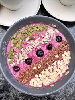Colorful smoothie bowl topped with seeds and berries in a Café 212 dish.