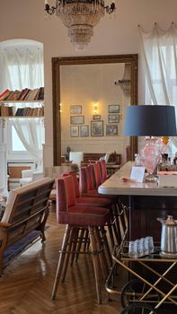 A cozy and elegant cafe interior featuring vintage decor, books, and a chandelier for a warm ambiance.