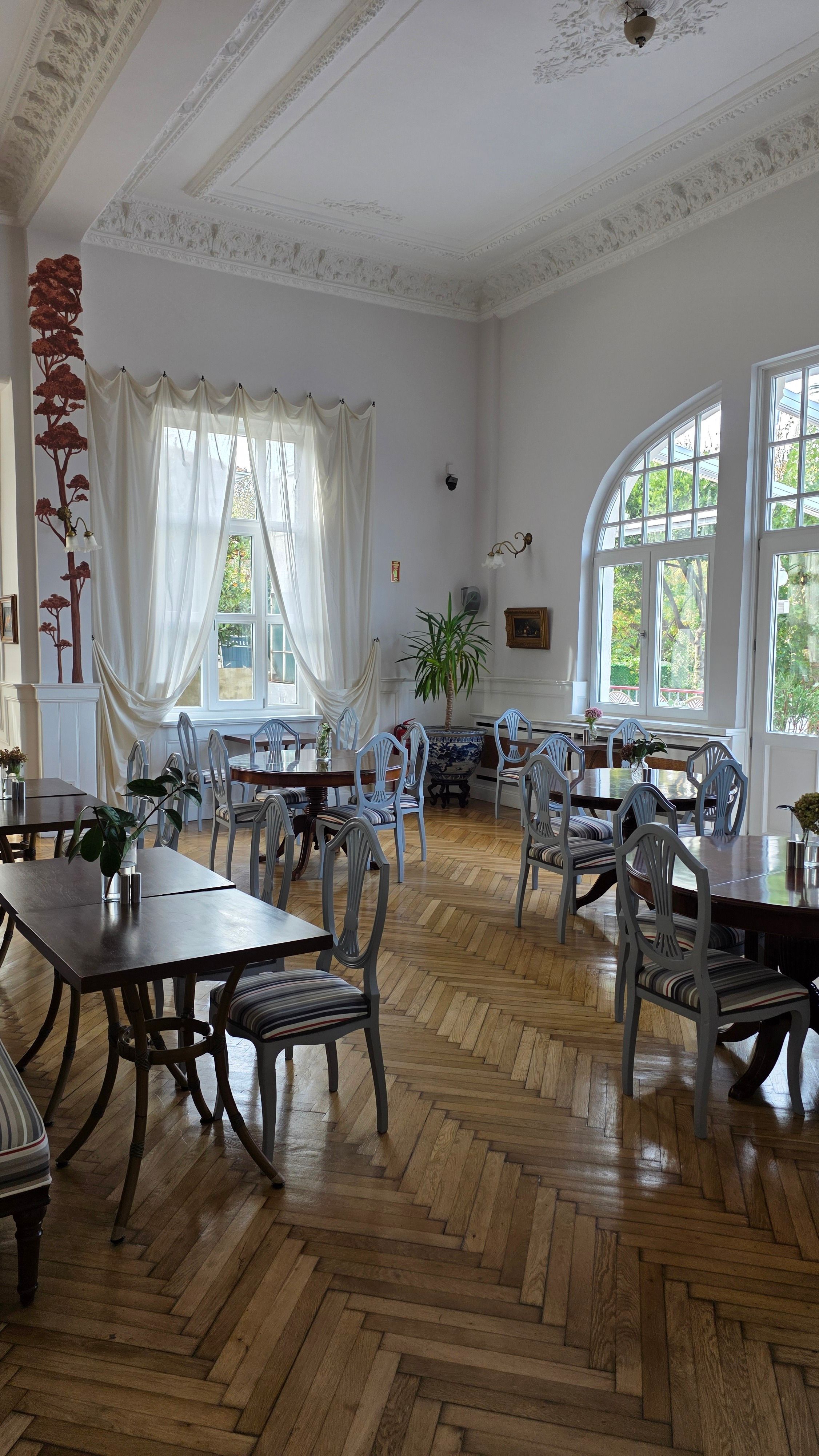 Bright vintage cafe with elegant wooden flooring, classic decor, and large windows.