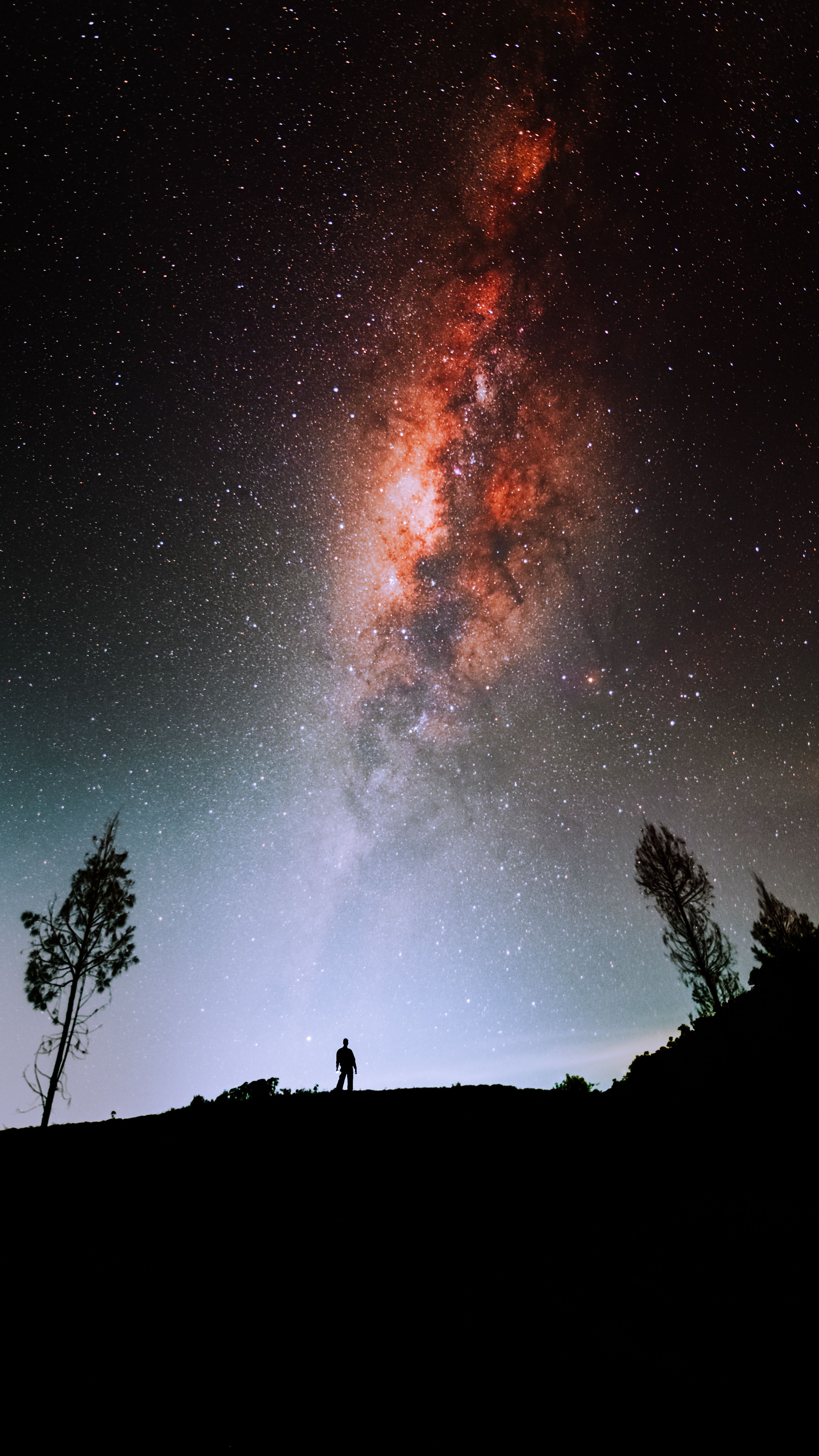 Stunning view of the Milky Way galaxy illuminating the night sky over East Java, Indonesia, with a lone silhouette for scale.