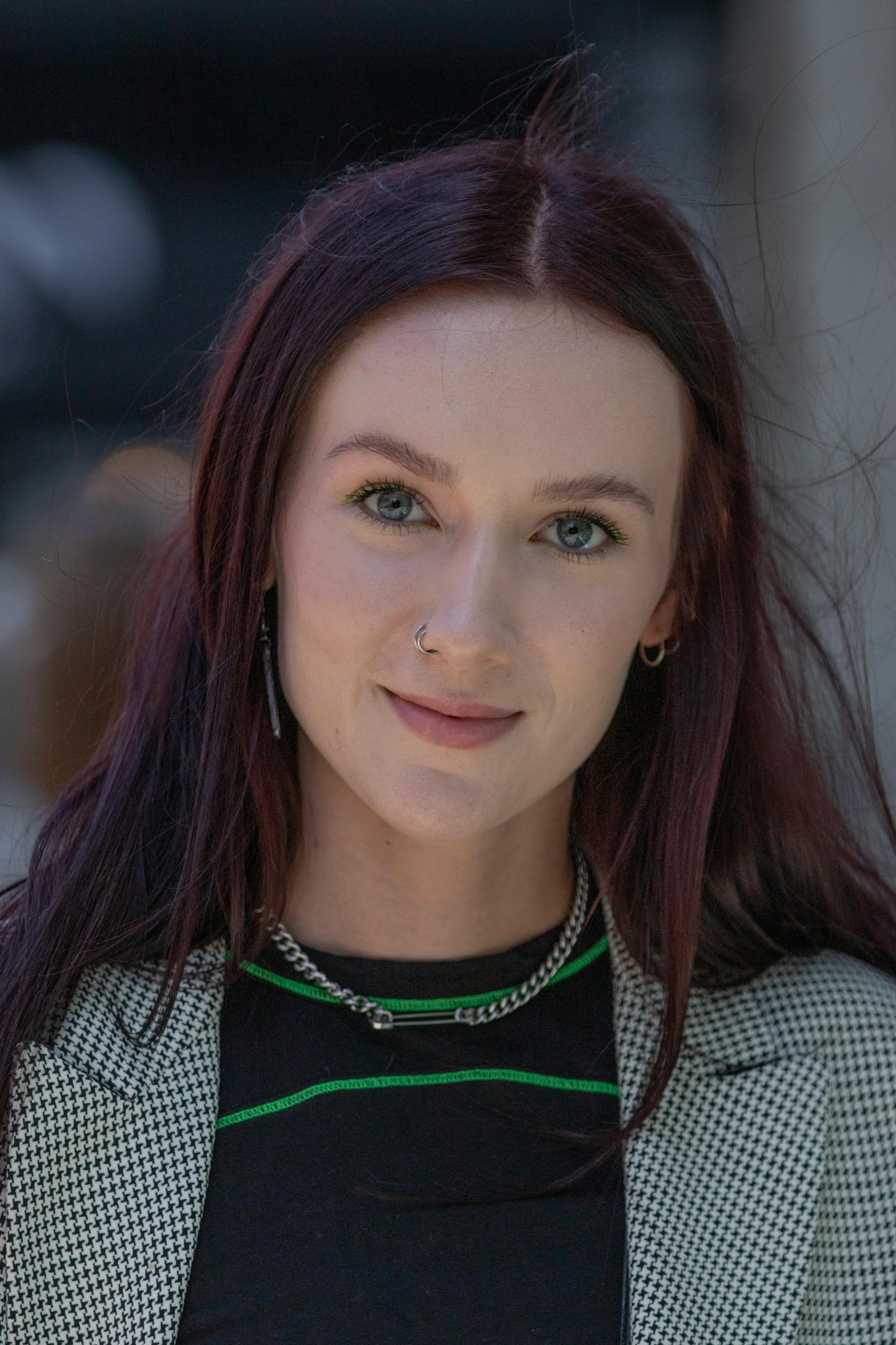 Close-up portrait of a young woman with dark hair and a nose ring, smiling softly.
