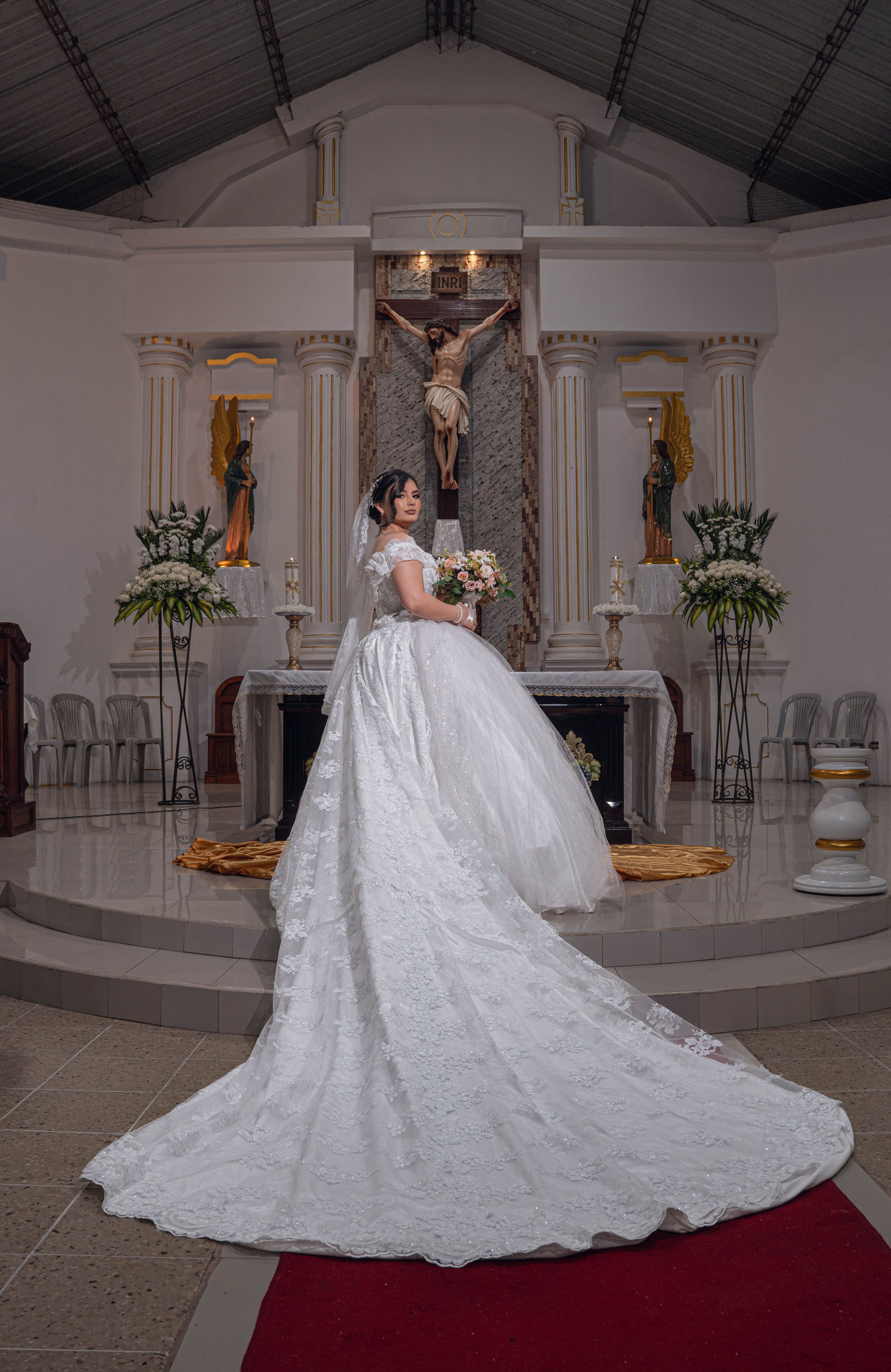 Bride in a church wearing a white gown, holding a bouquet, standing at the altar in Santo Domingo de los Tsáchilas, Ecuador.