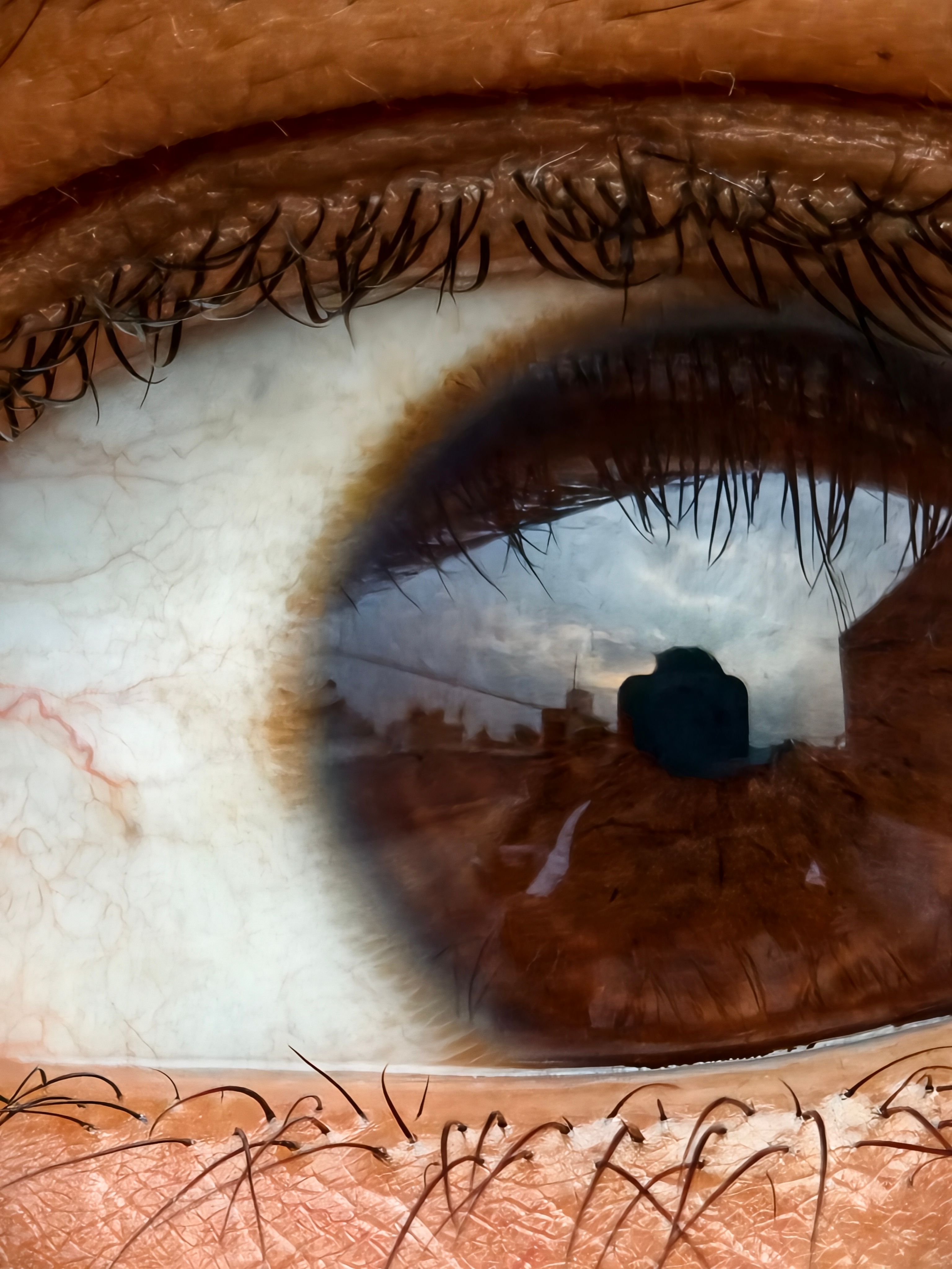 Detailed close-up of a human eye capturing a reflection of a camera and surrounding environment.