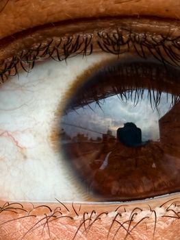 Detailed close-up of a human eye capturing a reflection of a camera and surrounding environment.