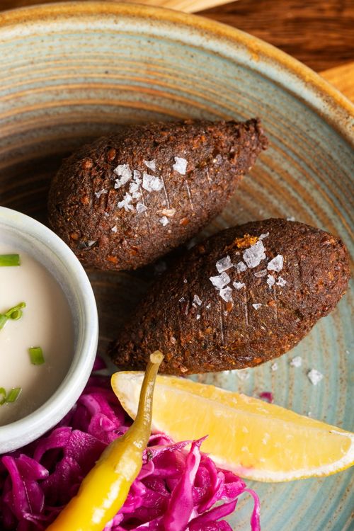 Free Delicious Middle Eastern kibbeh served with purple cabbage, lemon wedge, and sauce in Northbridge, WA. Stock Photo