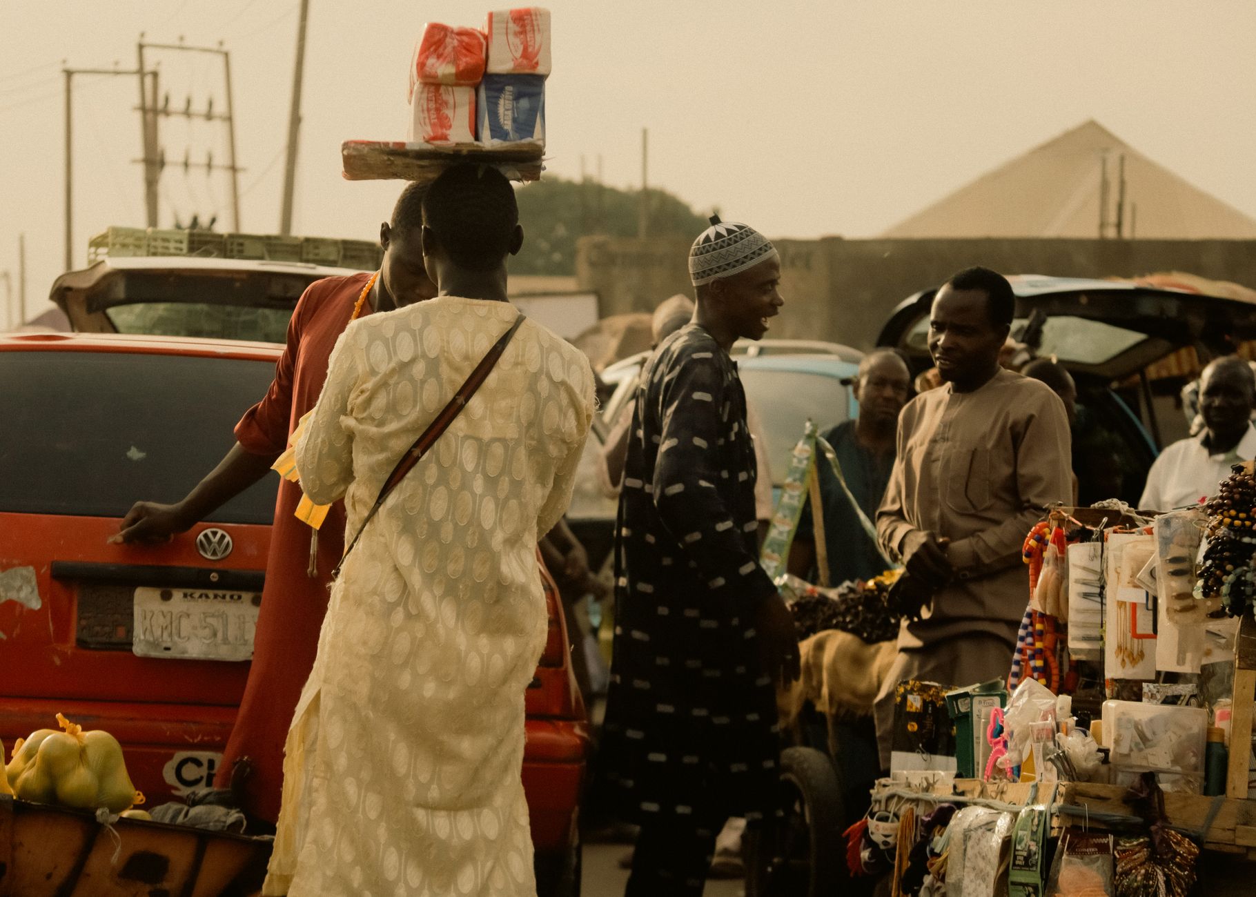 African market scene with people interacting, selling goods, and balancing items on their heads.