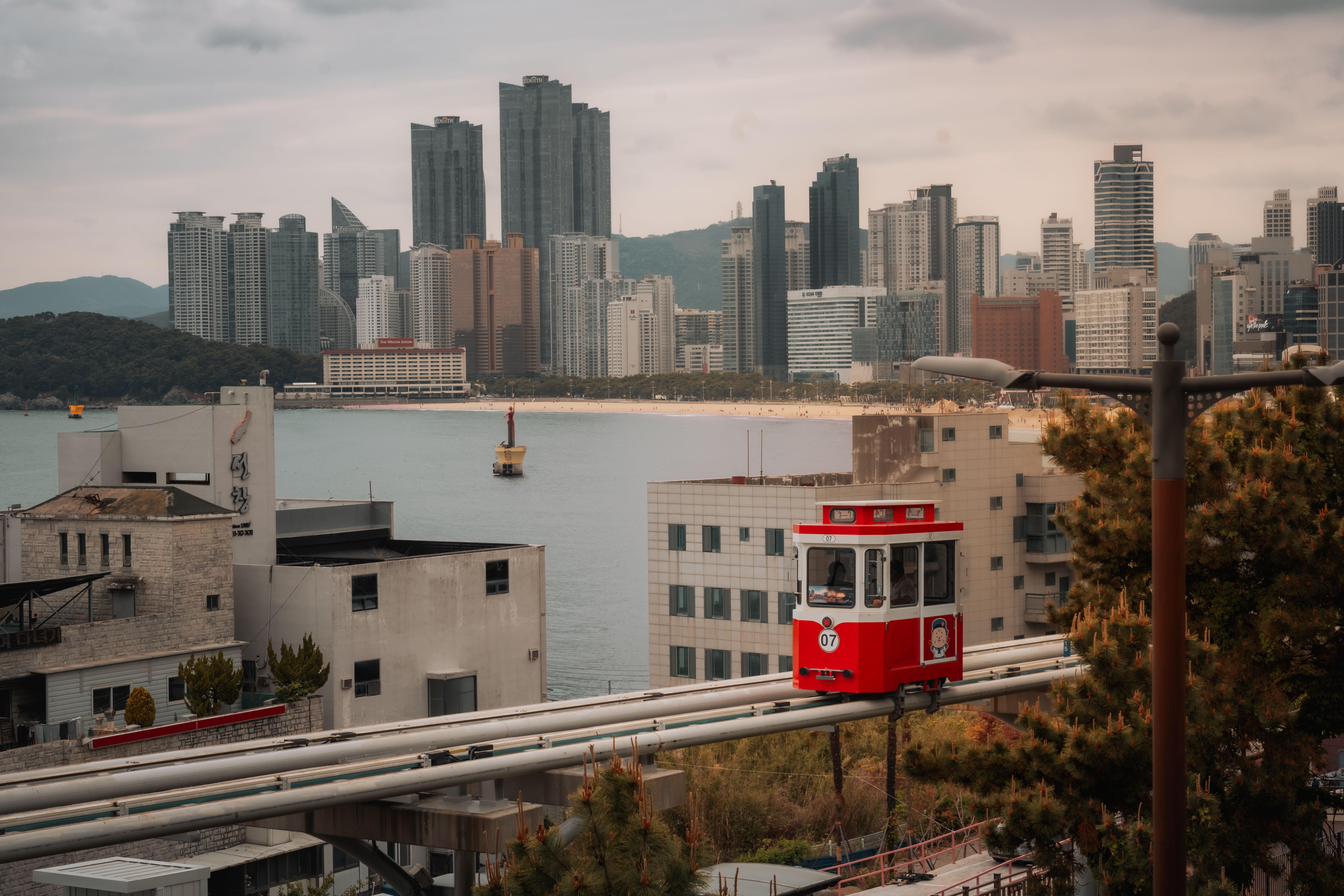 Stunning urban scene showing a monorail with Busan's skyline and coastline in the backdrop.