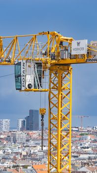 Tall yellow crane above a cityscape under a clear blue sky, symbolizing urban development.