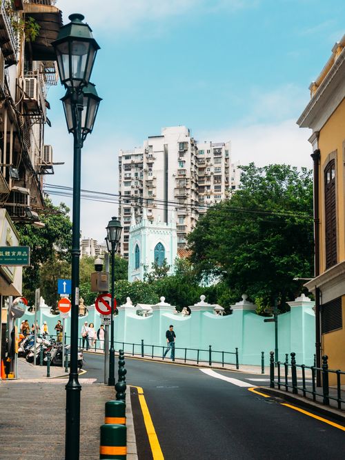 Free Picturesque street view in a city intersection with urban buildings and greenery, showcasing architectural contrast. Stock Photo