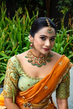 Beautiful South Indian bride in traditional attire with intricate jewelry, captured outdoors.