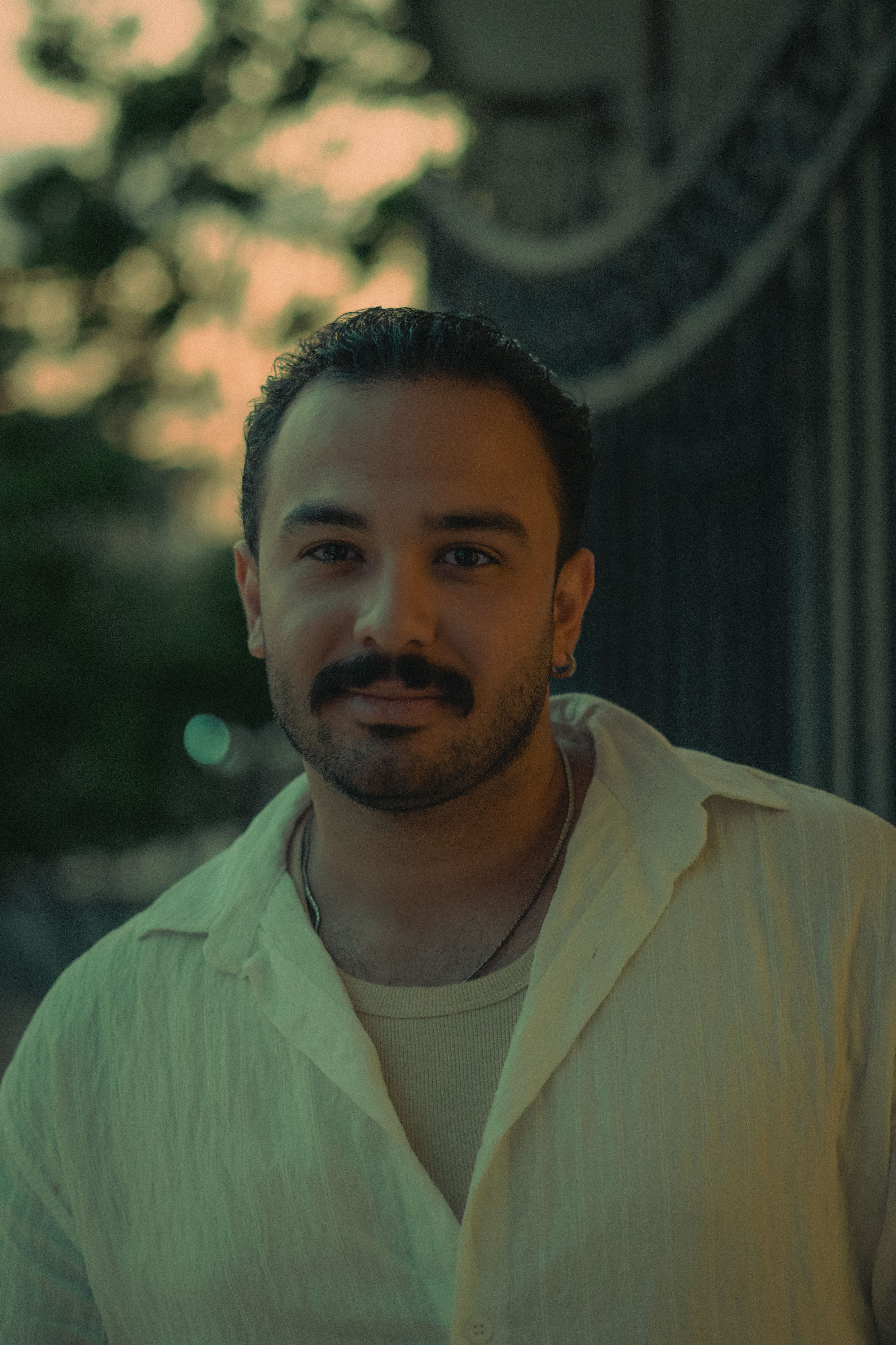 A serene outdoor portrait of a man with a mustache at twilight, featuring soft lighting and a calm ambience.