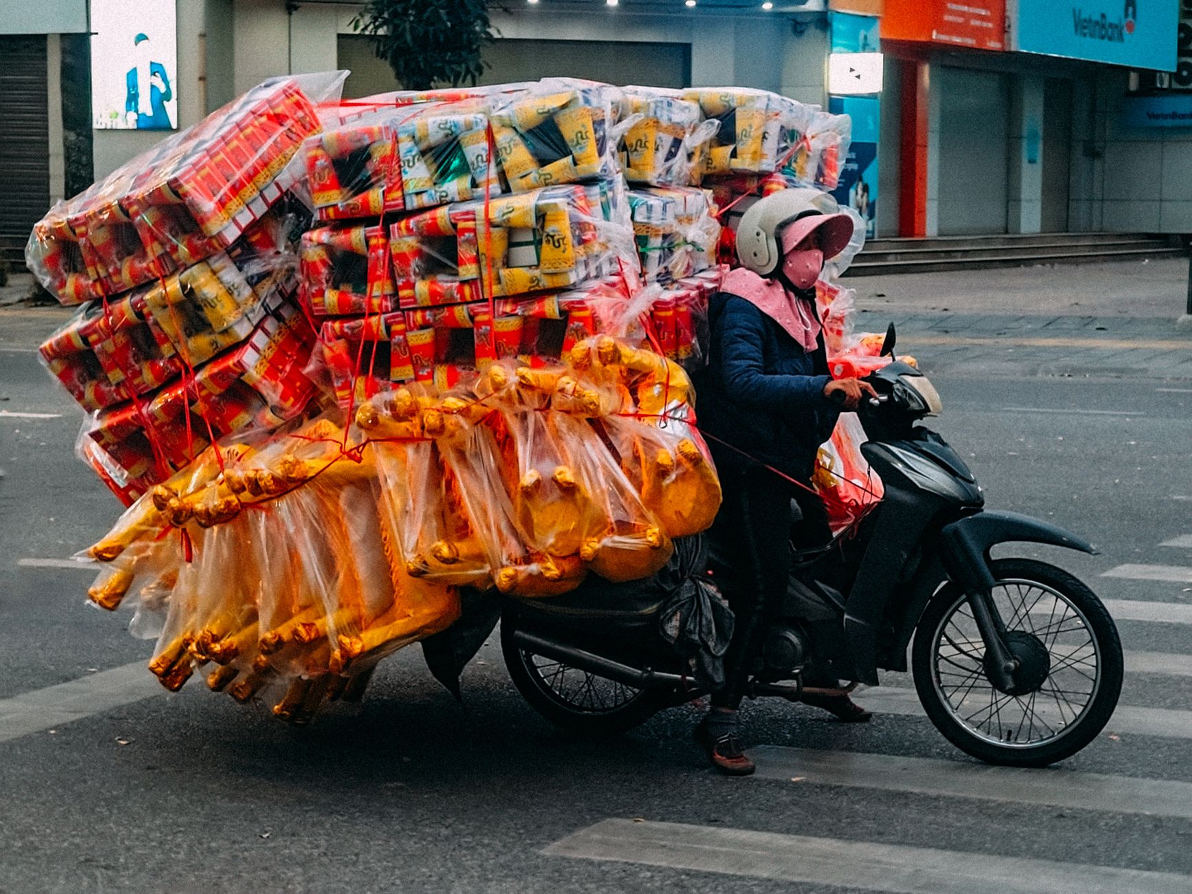 A motorbike rider transports goods piled high on a busy street in Bắc Ninh, Vietnam.
