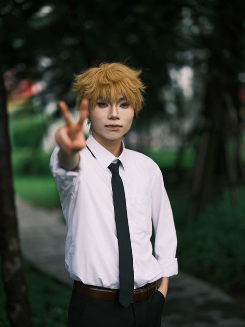 Free Cosplayer wearing a white shirt and black tie poses with a peace sign outdoors in Vietnam. Stock Photo
