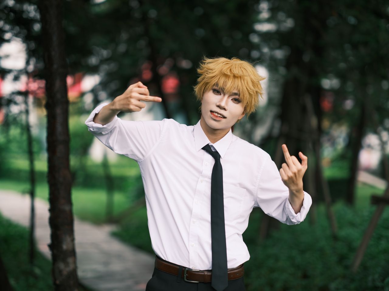 young adult cosplayer with blonde wig posing playfully in an outdoor p