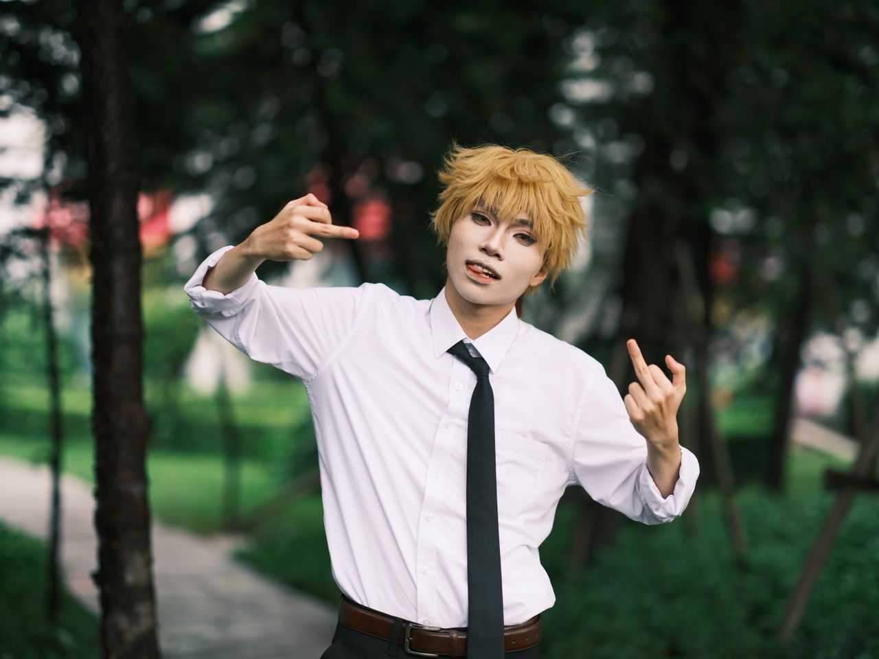 a cosplayer energetically poses in a park showcasing expressive cospla