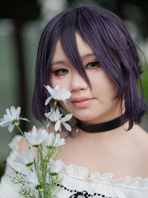 Free Portrait of a cosplayer holding white flowers with a dreamy expression in Vietnam. Stock Photo