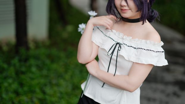 A young woman in a white off-shoulder dress with flowers, styled for cosplay, outdoors in Vietnam.