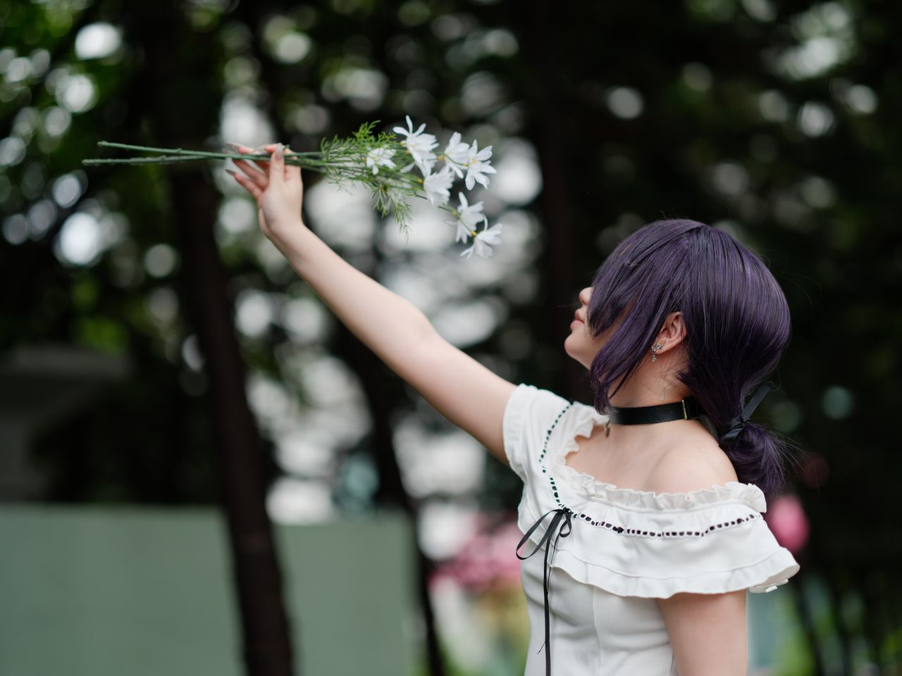 side profile of a cosplay enthusiast holding white flowers outdoors in