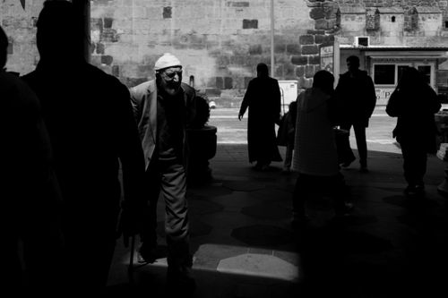 Free A black and white photo featuring silhouettes of people walking in an urban area, creating dramatic contrast. Stock Photo