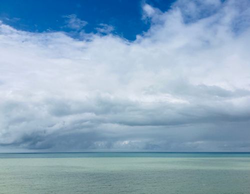 Free Tranquil ocean view with a vast sky and fluffy white clouds, creating a calming seascape. Stock Photo