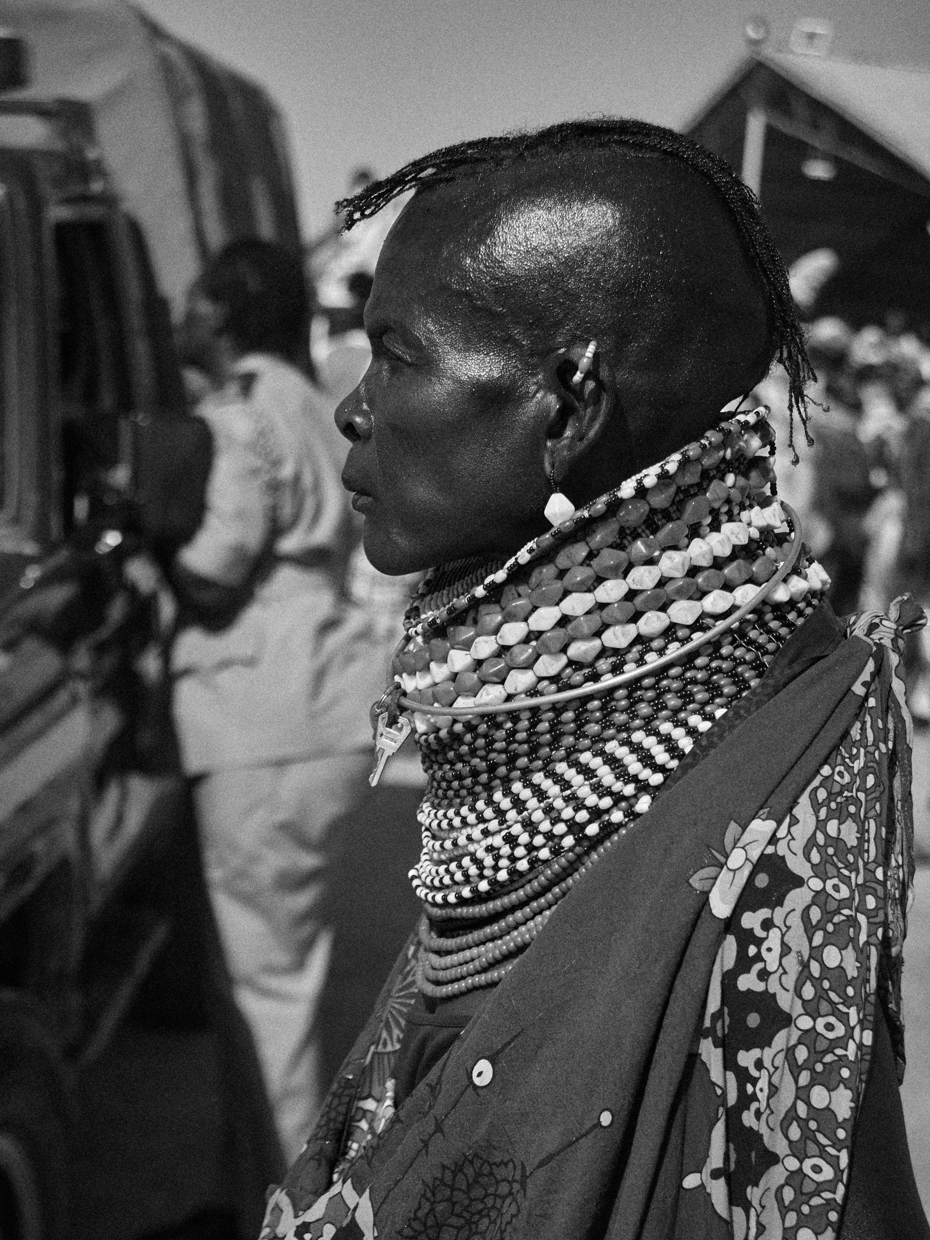 A profile view of a traditionally adorned person wearing tribal jewelry in a black and white setting.