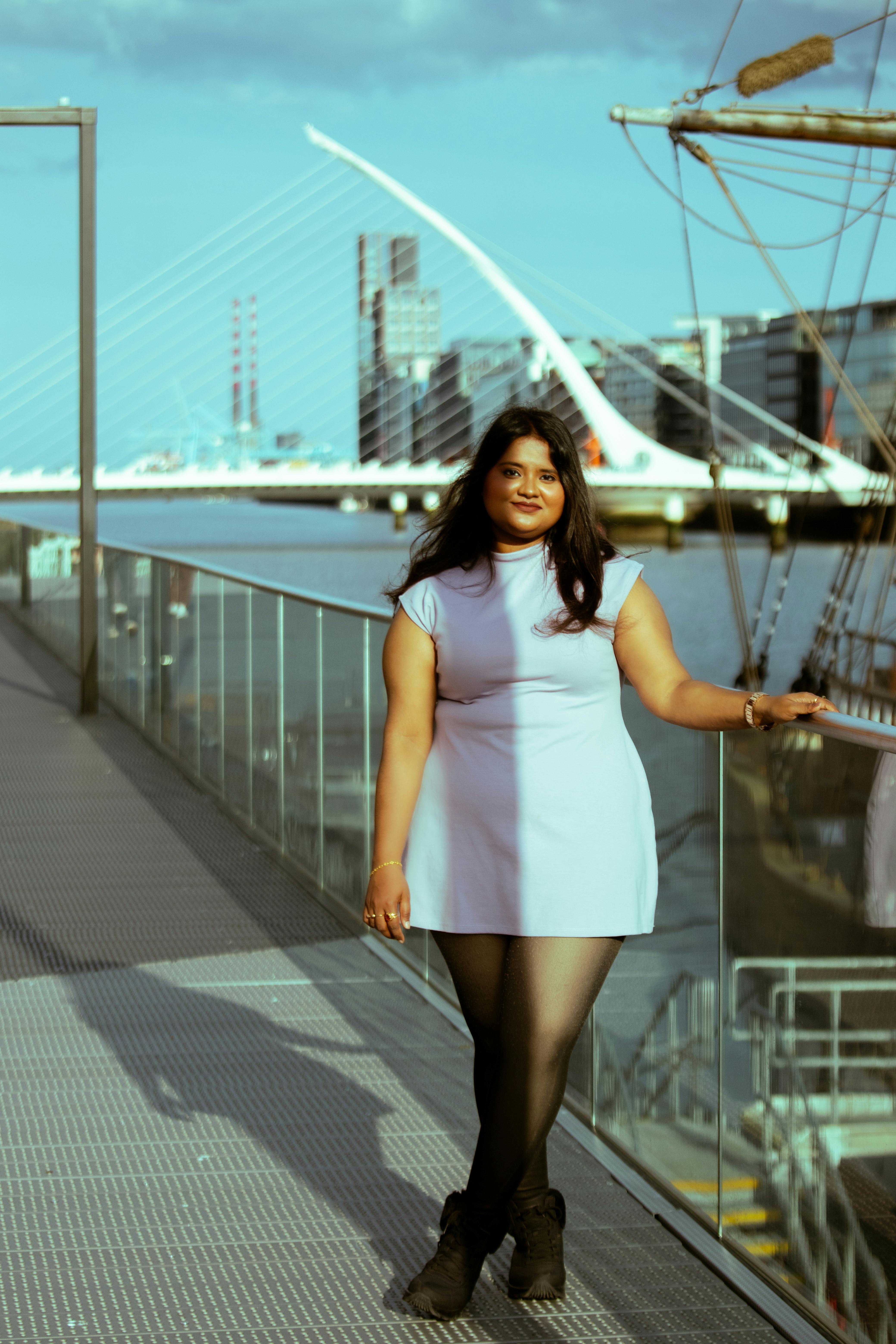 Woman in blue dress standing by Samuel Beckett Bridge in Dublin, Ireland during daytime.
