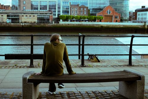 Free A man sitting peacefully on a bench by the riverfront in Dublin, Ireland. Stock Photo