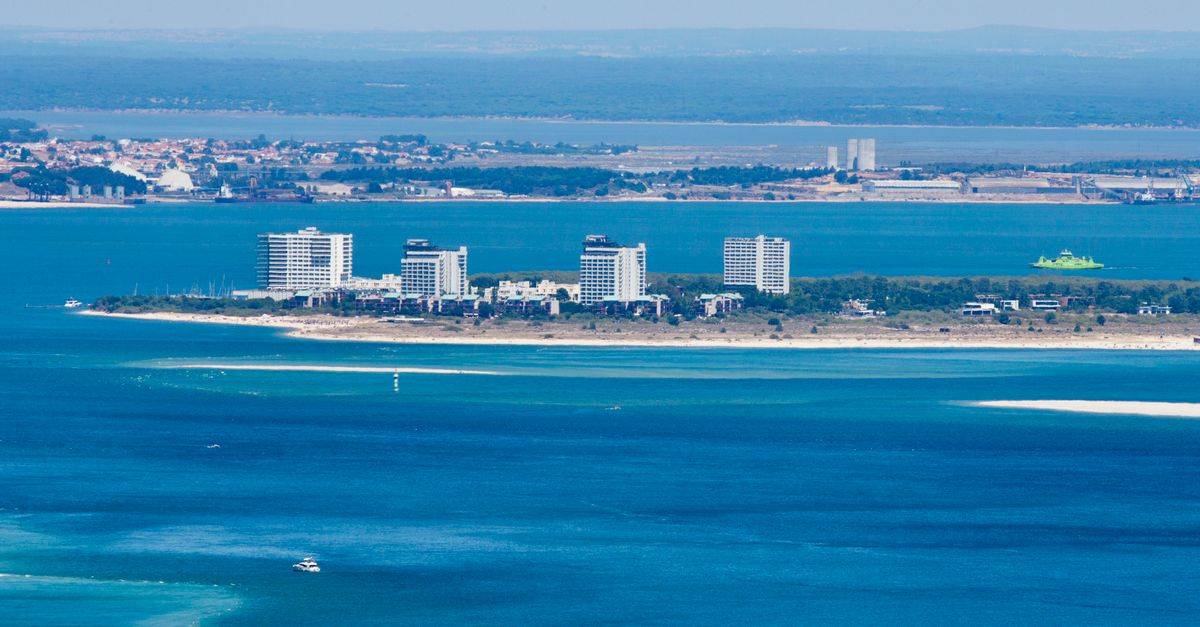 A stunning aerial view of a cityscape along the coast with vibrant blue ocean water.
