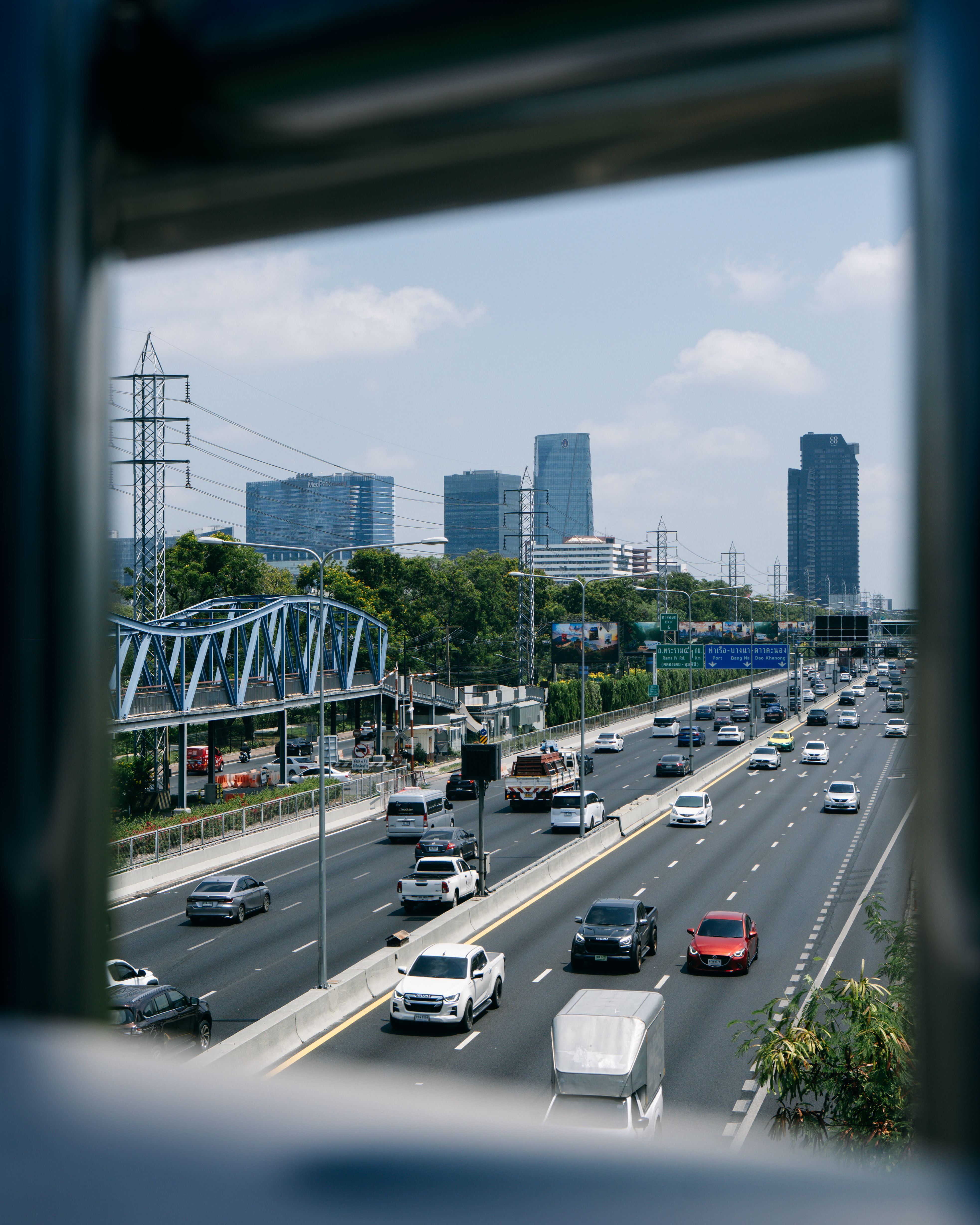 A busy Thai highway with modern skyscrapers in the background, representing the Bangkok-Korat road transfer