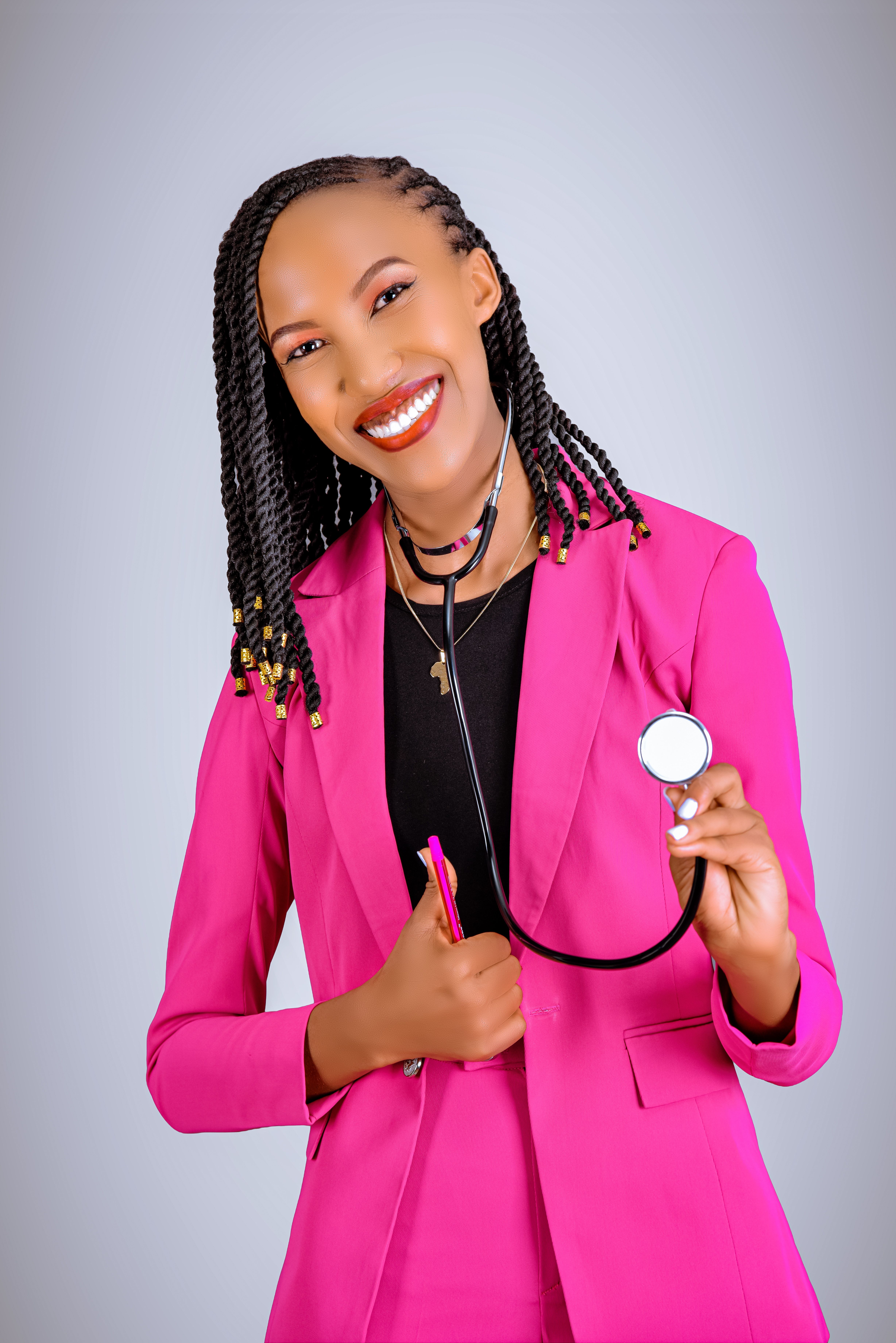 Portrait of a smiling female doctor wearing a pink blazer, holding a stethoscope, symbolizing healthcare professionalism.