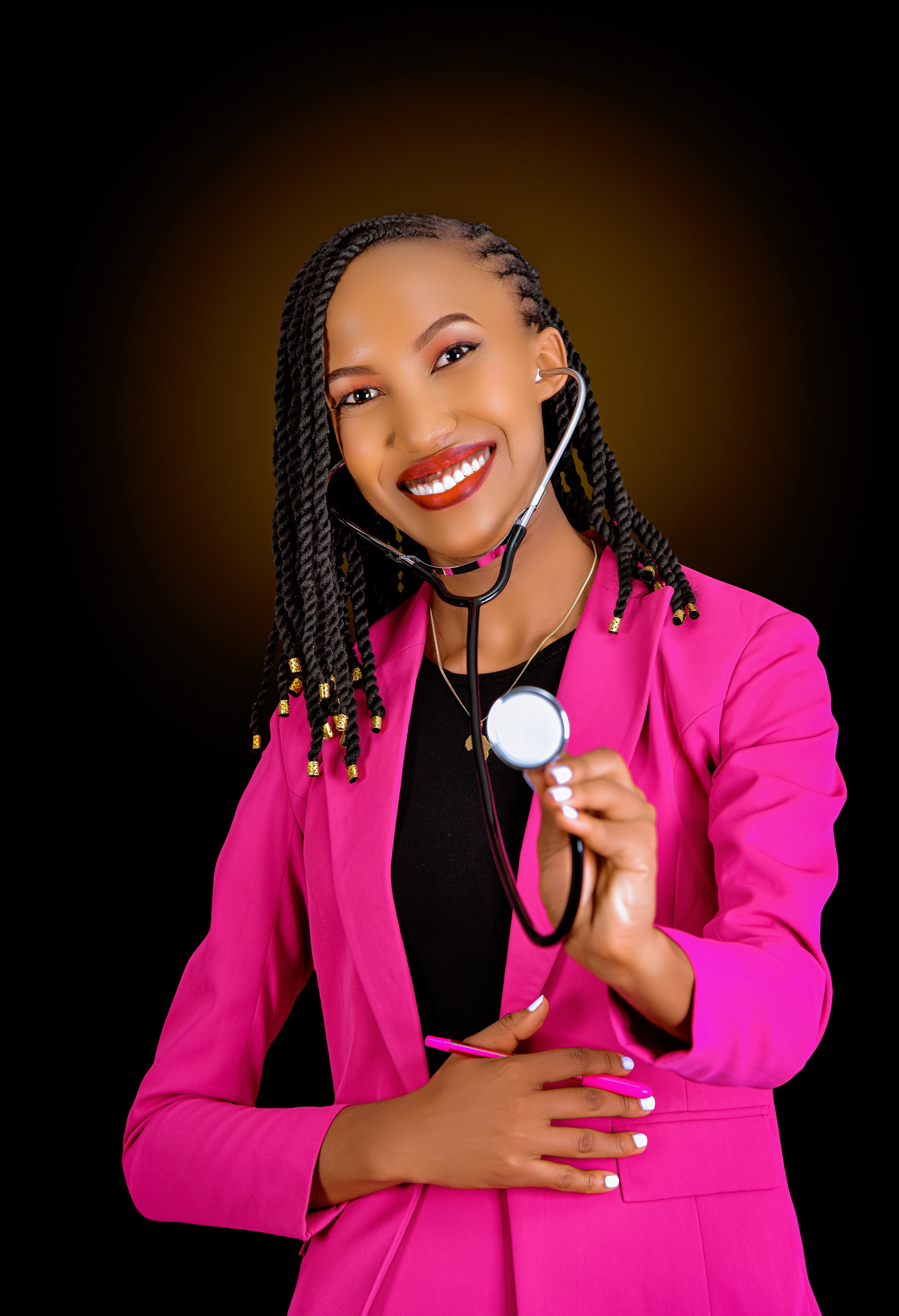 Smiling African female doctor in pink blazer holding a stethoscope against dark background.