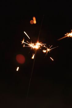 A close-up of a lit sparkler with bright sparks against a dark background, capturing the essence of celebration.