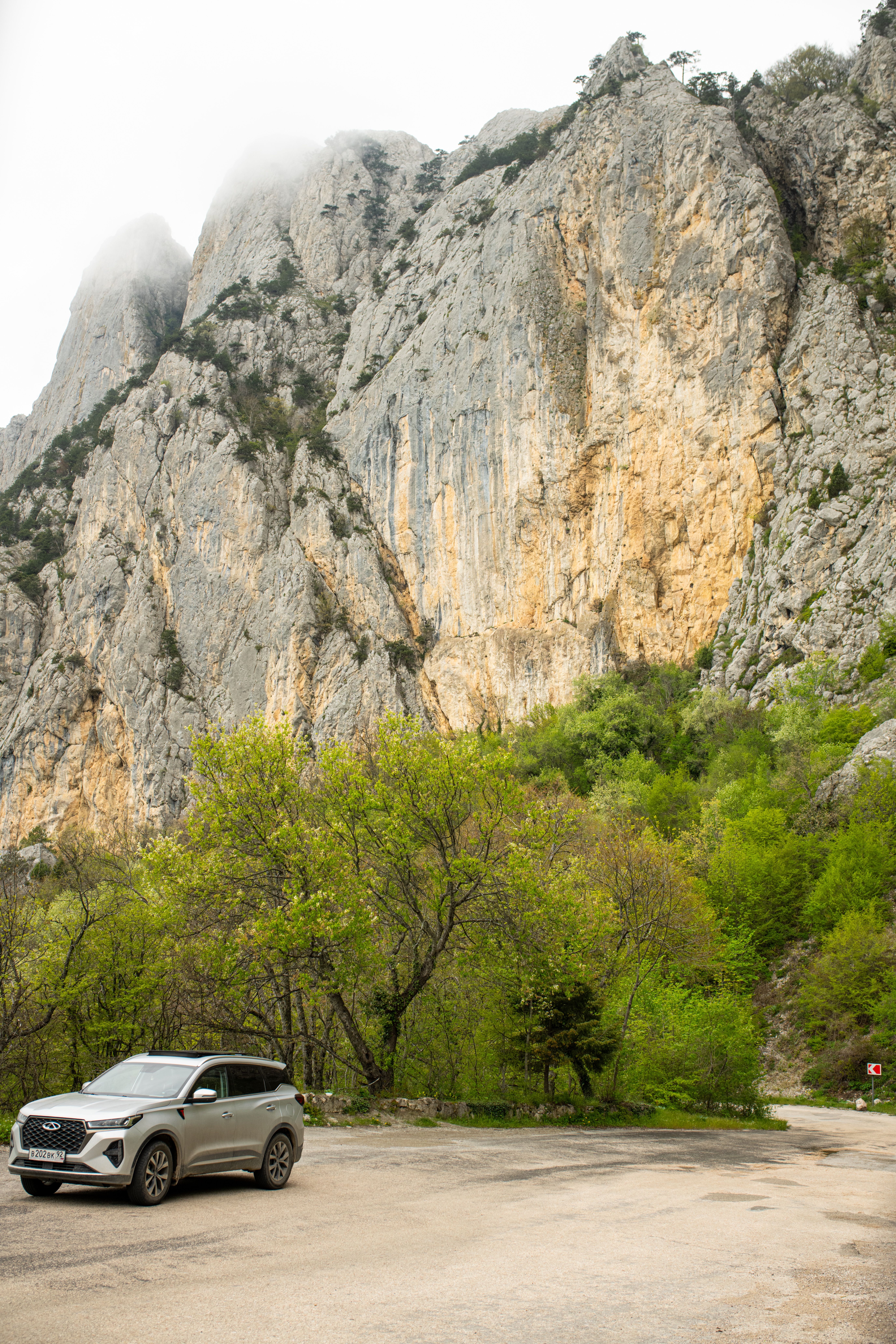 Stunning view of rocky cliffs in Crimea with an SUV parked in the foreground, showcasing natural beauty.