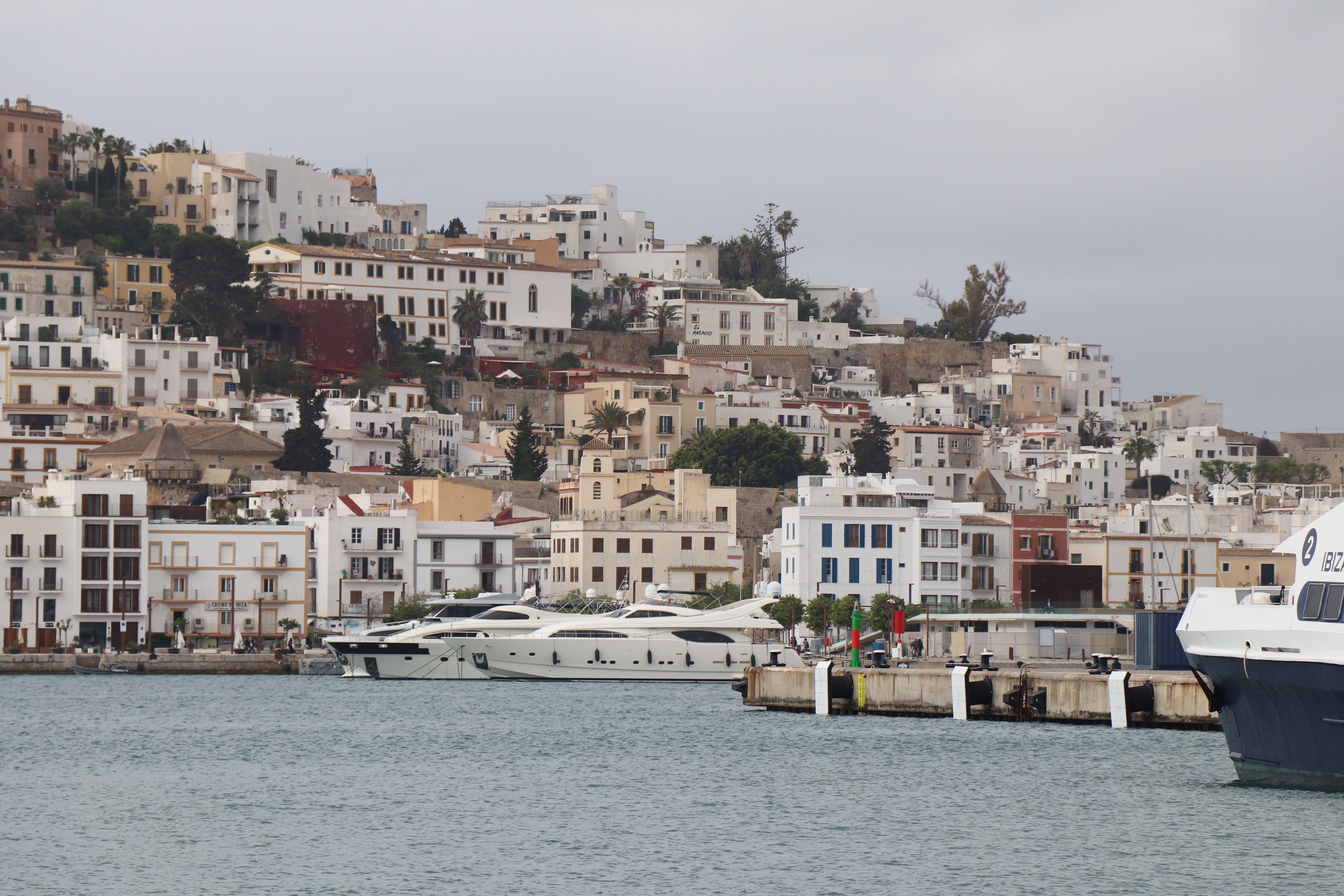 Panoramic view of Ibiza's old town architecture and luxury yachts in the marina, Balearic Islands.