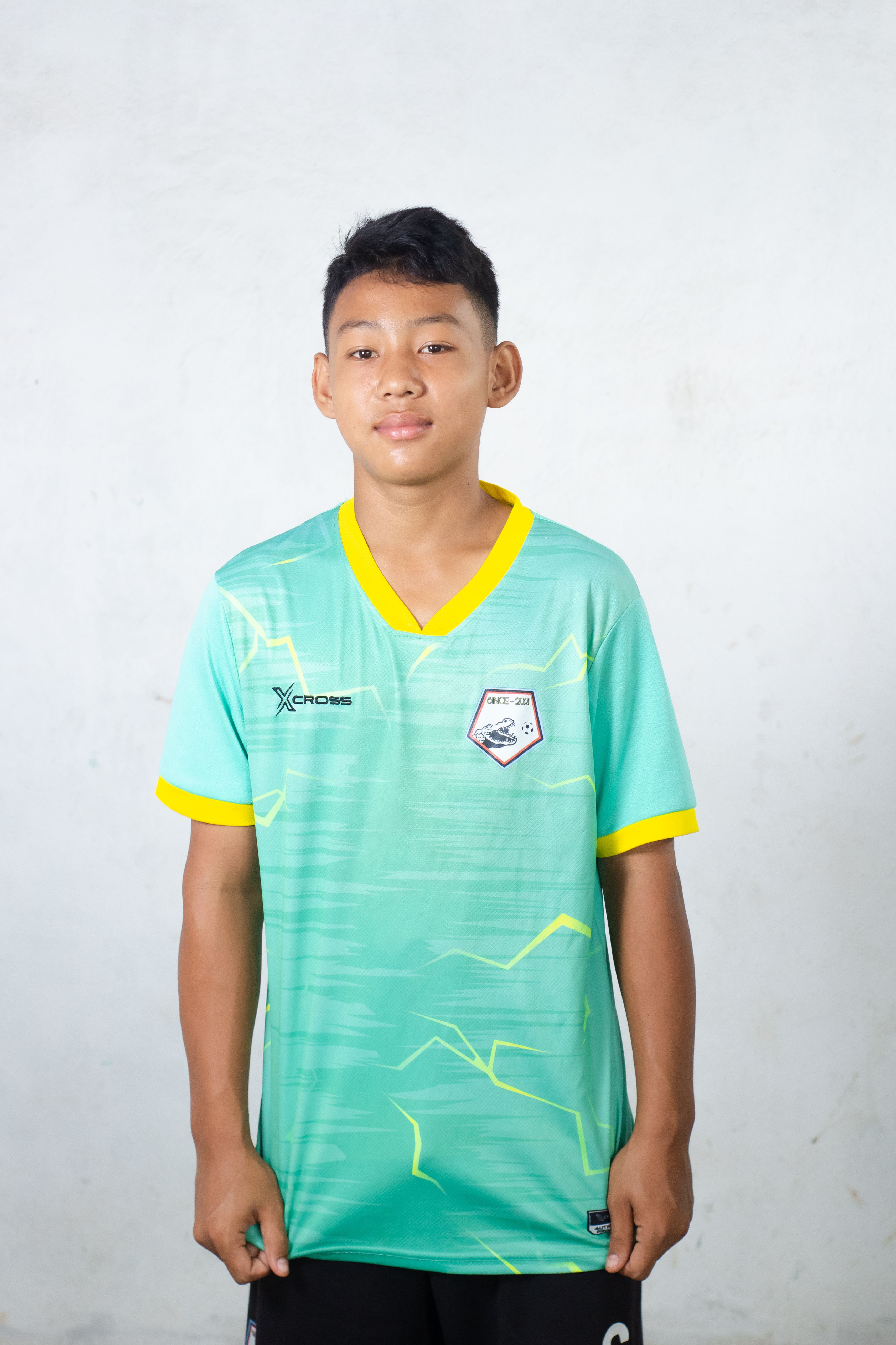 Portrait of a teenager in a sports jersey with a neutral background.