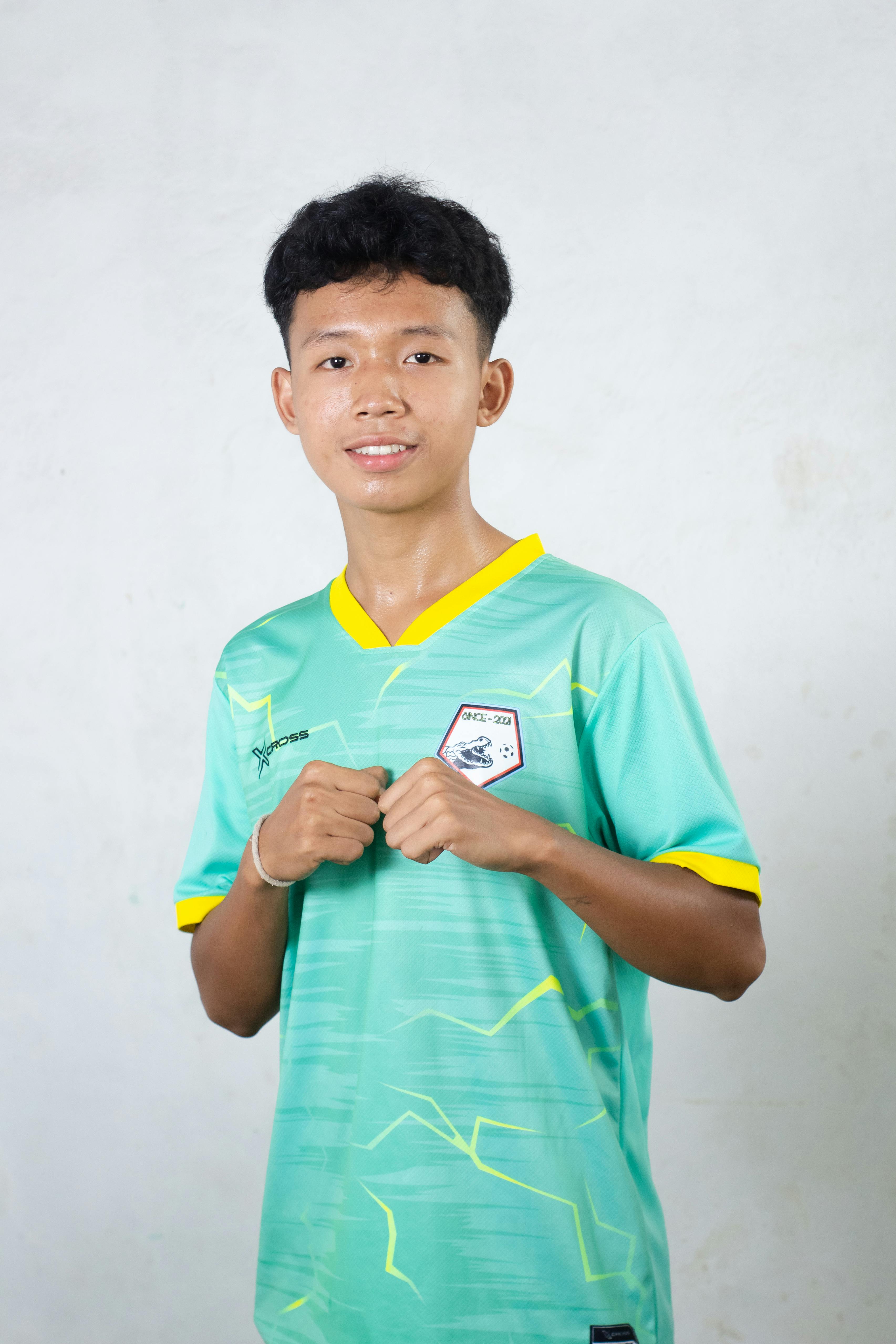 Portrait of a young male athlete in green sporting gear, standing confidently against a plain background.