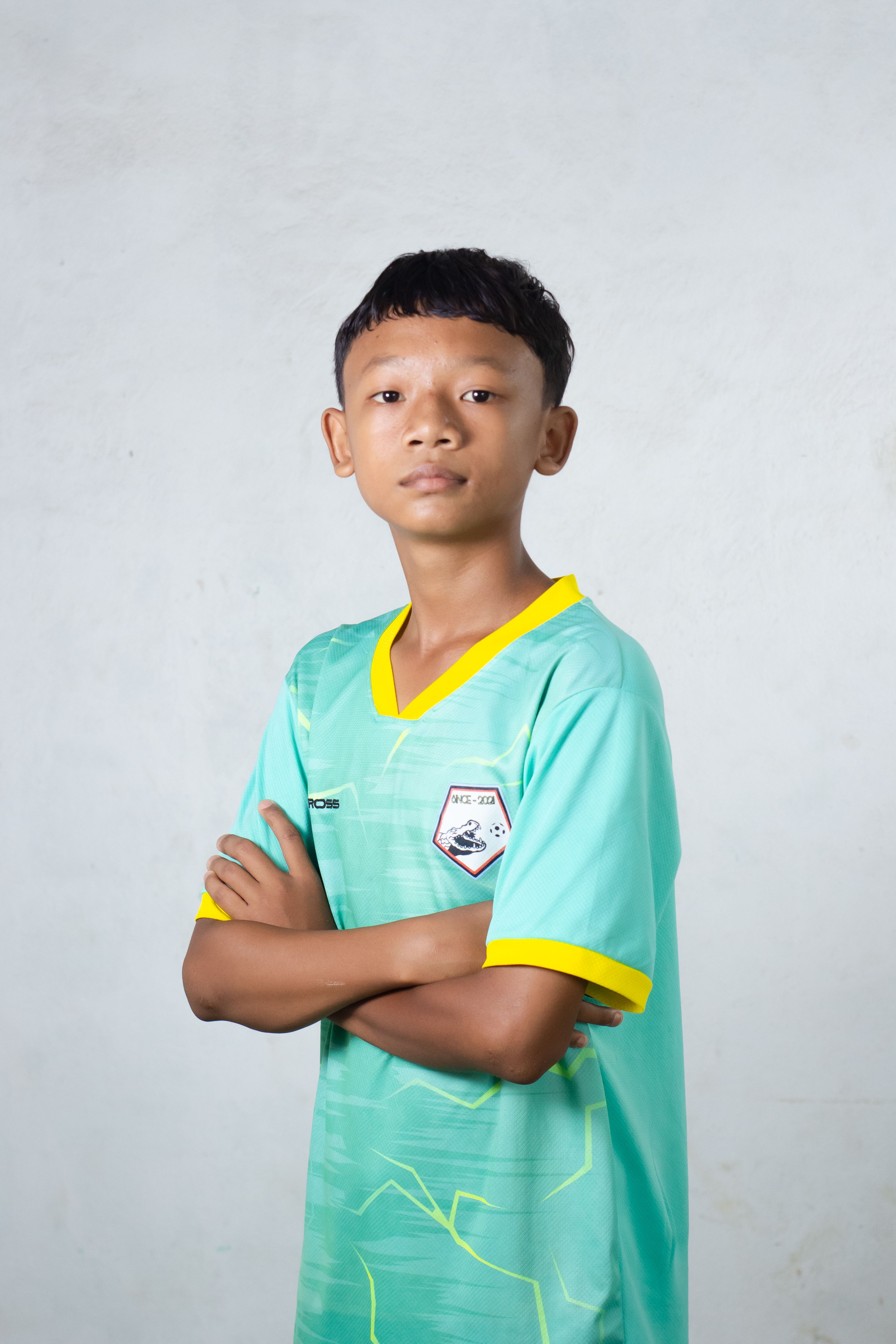 A young soccer player in a sports jersey poses confidently in a studio setting.