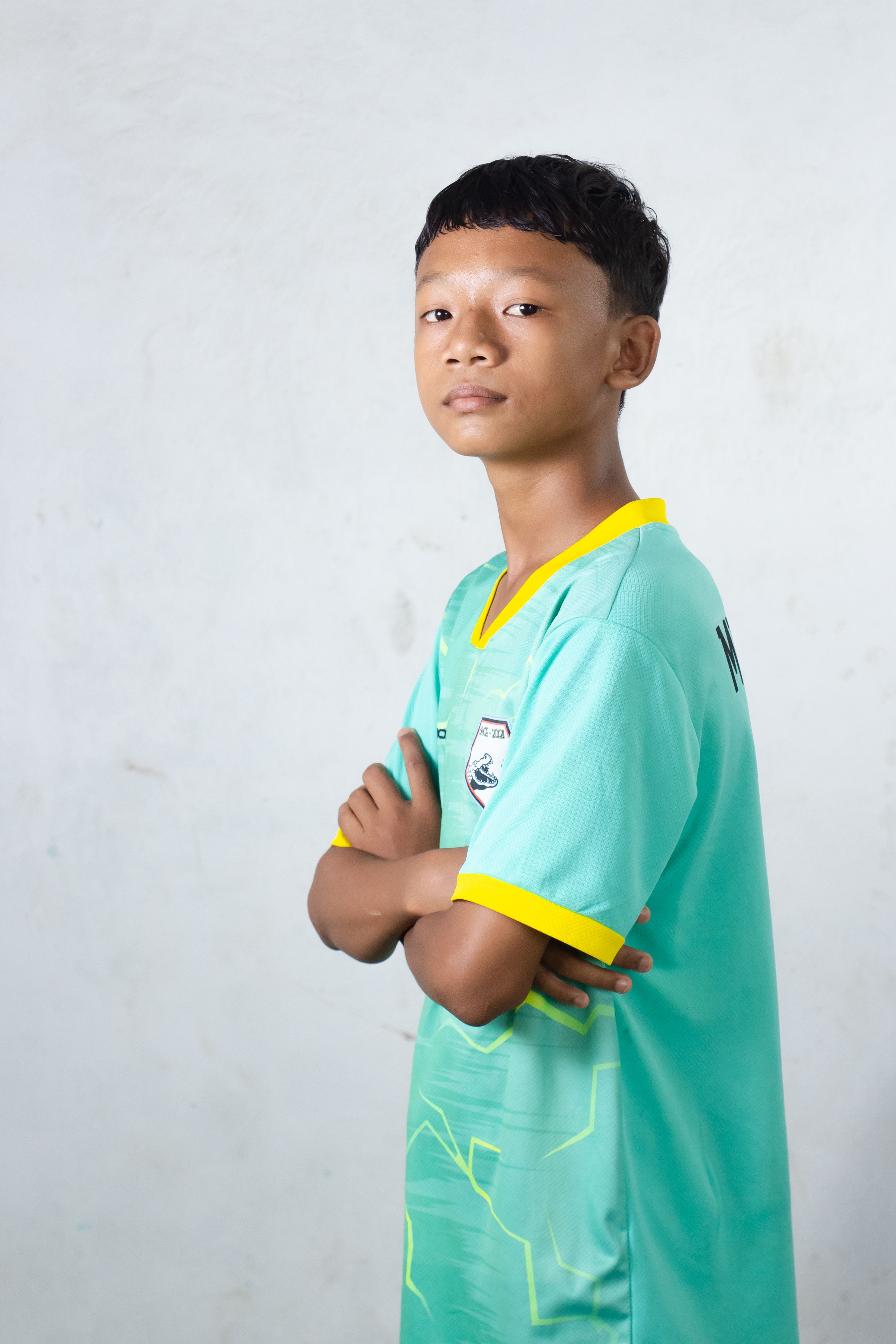 Confident young boy wearing a sports jersey posing indoors, showcasing determination.